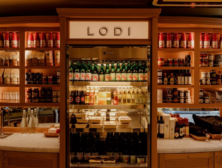 Wooden shelving display filled with various Italian food products, wines, and gourmet items with LODI signage above