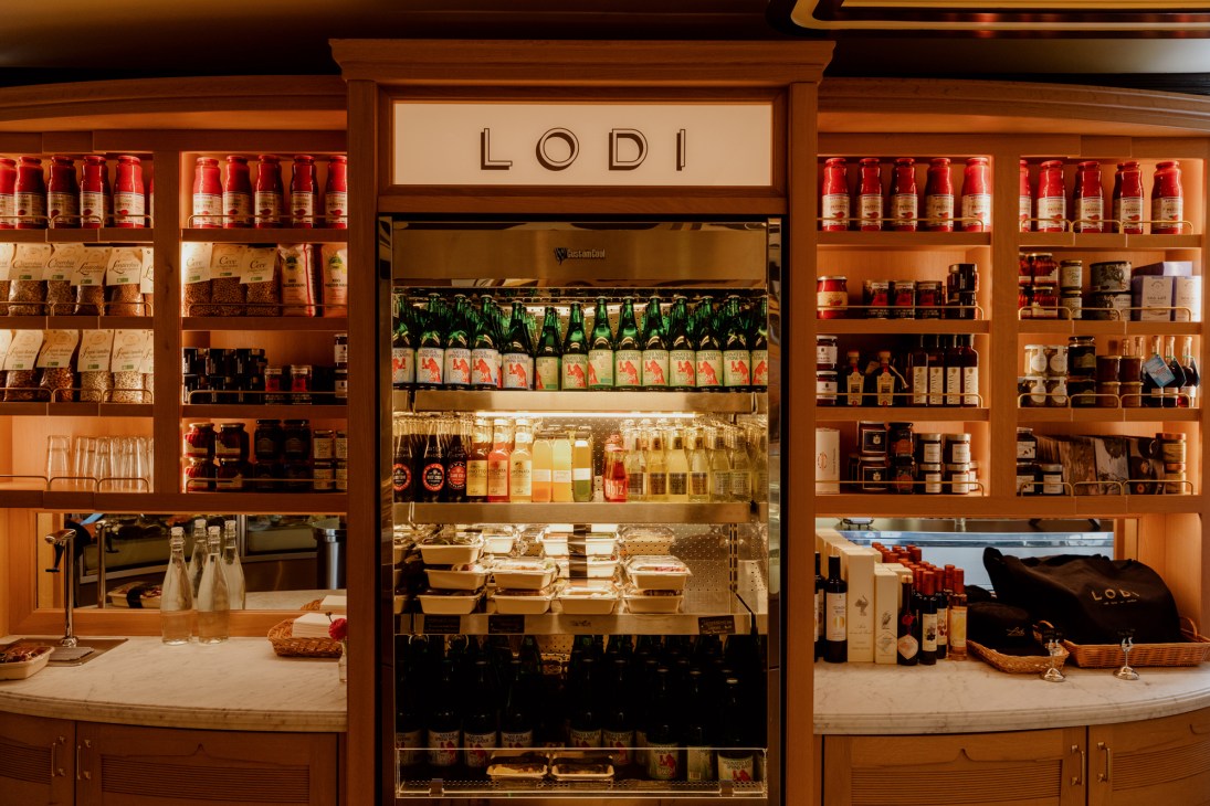Wooden shelving display filled with various Italian food products, wines, and gourmet items with LODI signage above