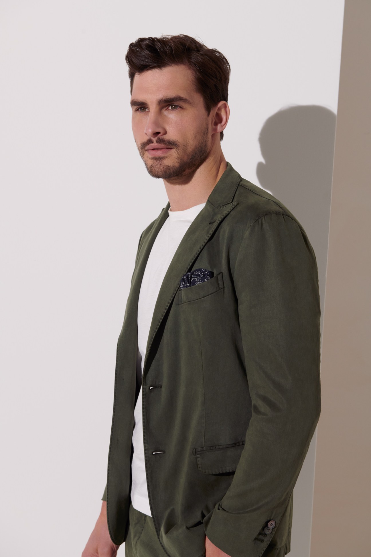 Man wearing olive green Boglioli suit jacket and trousers with white De Bonne Facture t-shirt and Drake's pocket square