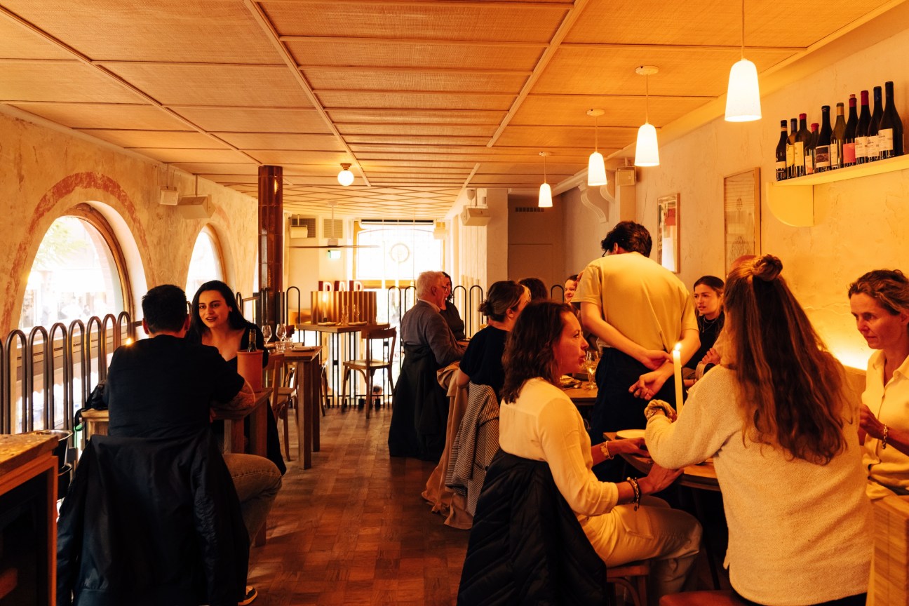Mezzanine level at Gitane restaurant showing rattan ceiling and terrazzo surfaces with diners seated at tables