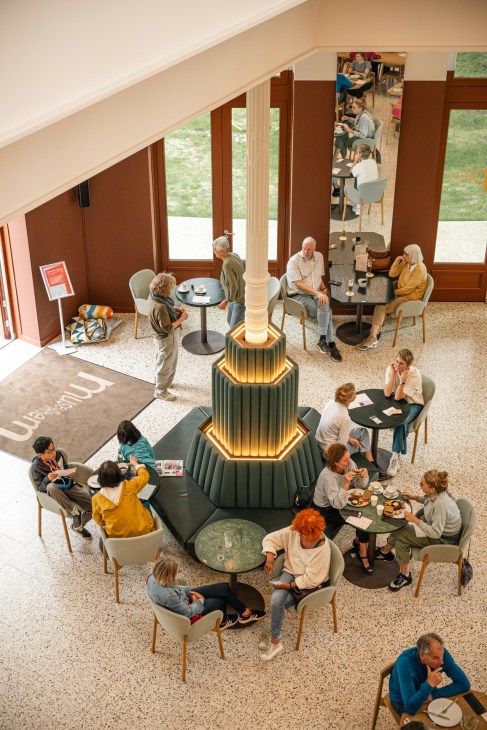 Museum Arnhem's café area featuring contemporary design with neon chandelier installation