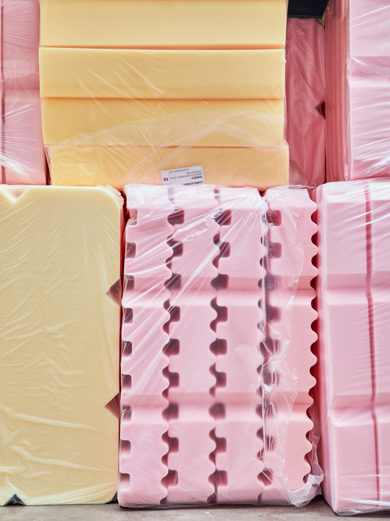 Cut sections of polyurethane foam padding material in yellow and pink colors wrapped in plastic