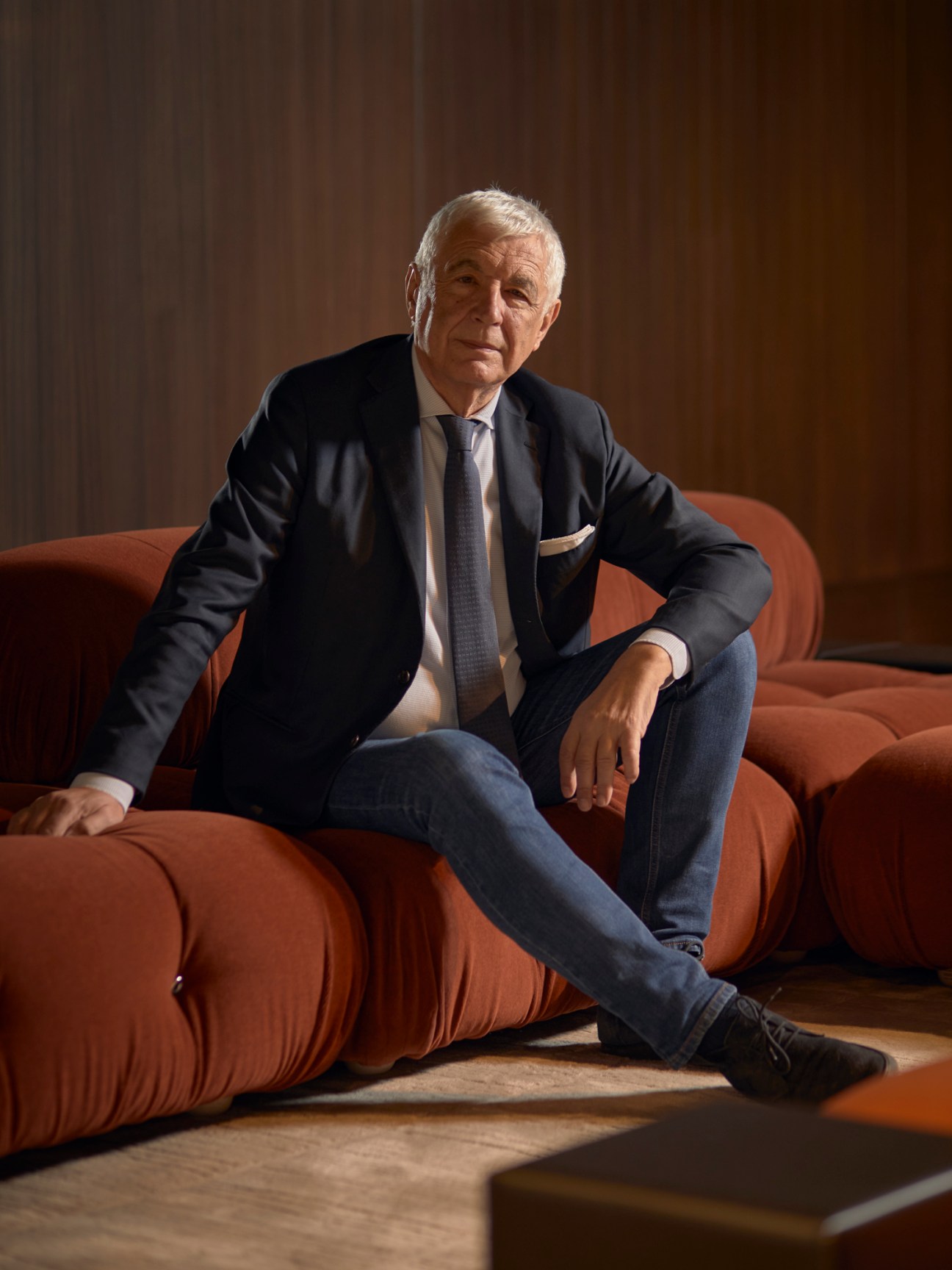 Gabriele del Torchio, Design Holding's chairman and CEO, sitting in business attire on an orange sofa