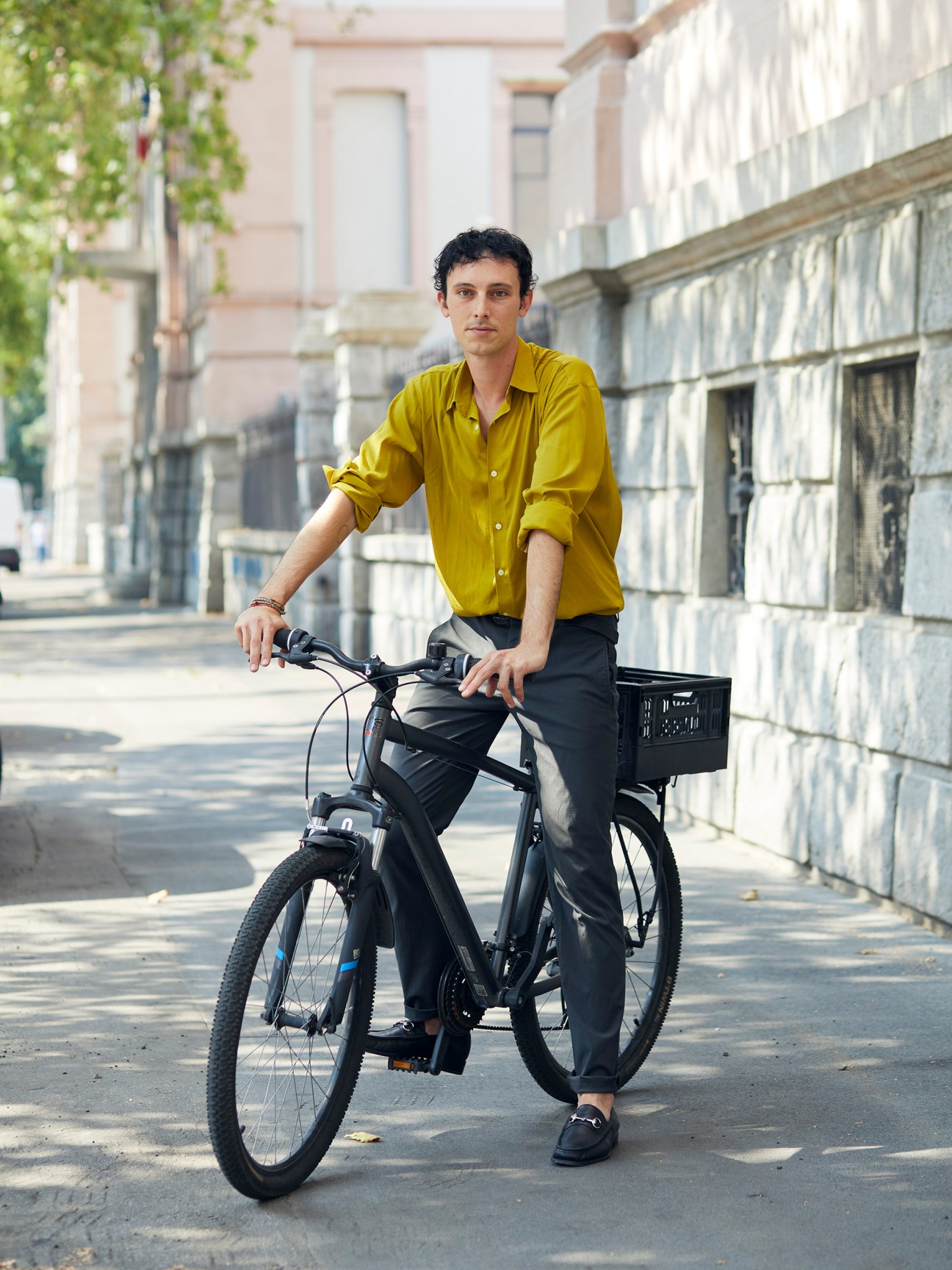 Fashionable woman cycling through Milan wearing coat and carrying handbag