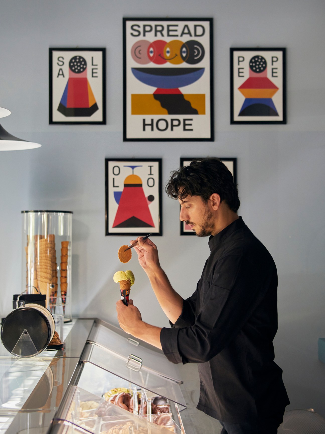 Man in black shirt holding ice cream cone at Giass gelateria in Milan with colorful wall art