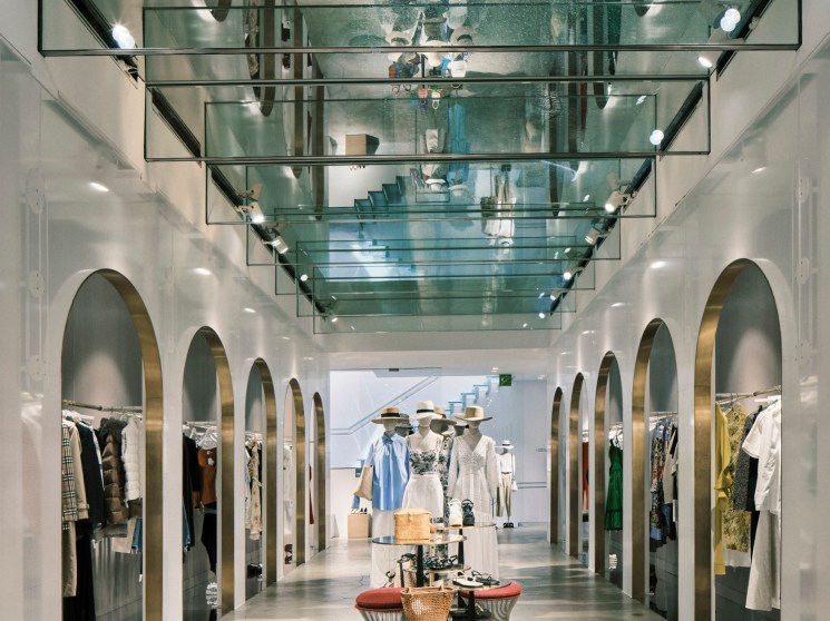 A mirrored hall inside Luisa Via Roma department store with arched alcoves displaying designer clothing and mannequins.