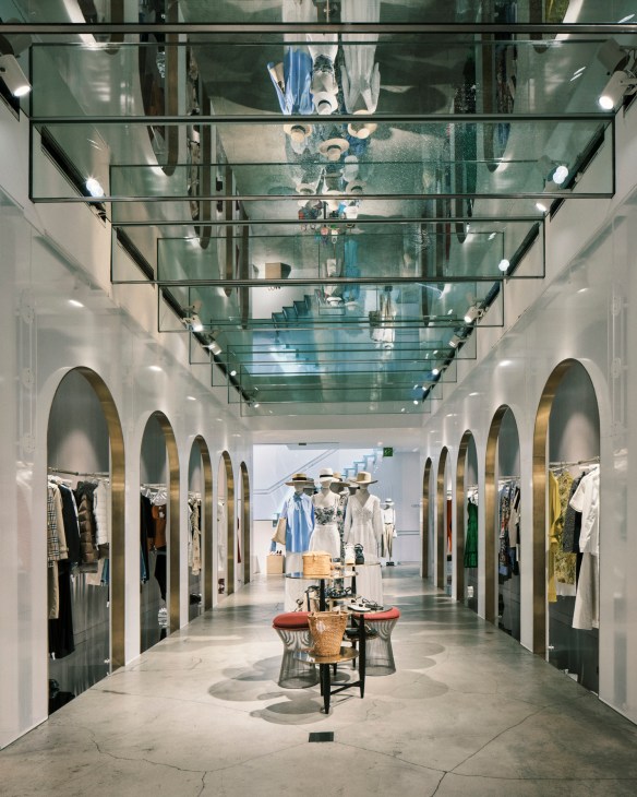 A mirrored hall inside Luisa Via Roma department store with arched alcoves displaying designer clothing and mannequins.