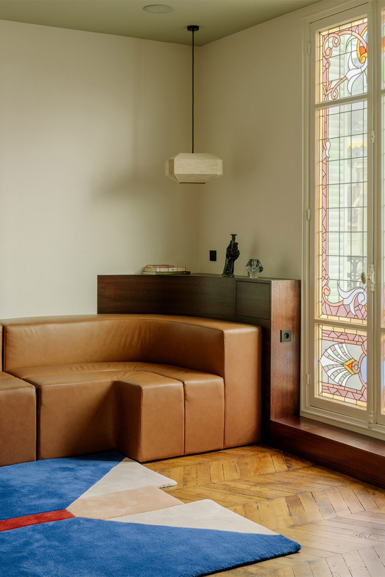 Contemporary interior with curved tan leather sofa, stained glass windows, and custom black oak furniture by Louis Denavaut