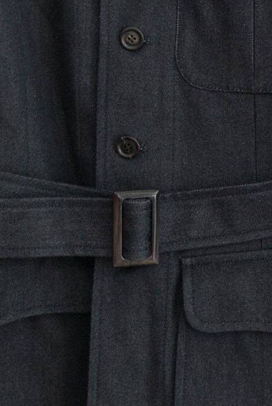Close-up of dark navy jacket with belt buckle and buttons showing tailored construction details