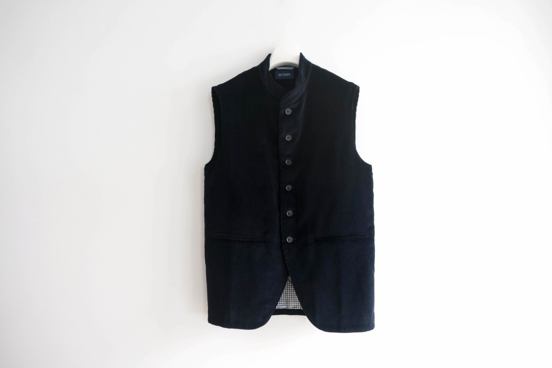 Black corduroy waistcoat with button-front closure and stand collar displayed against white background