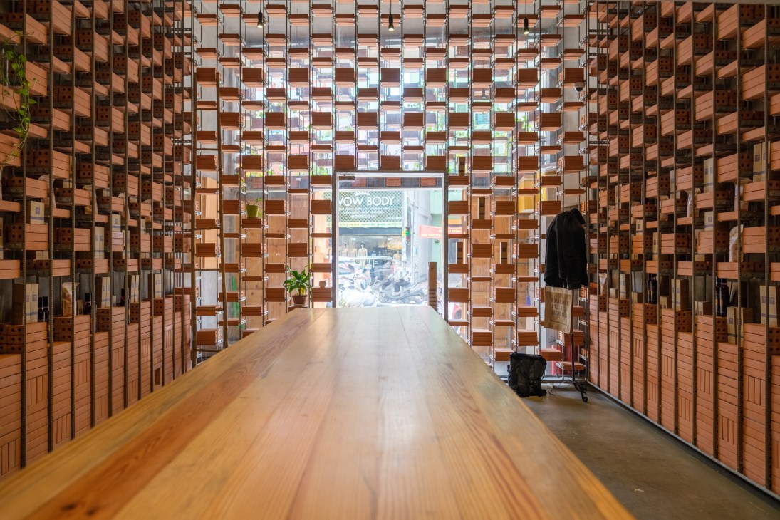 Interior corridor of a brick building with wooden floors and geometric patterned windows.