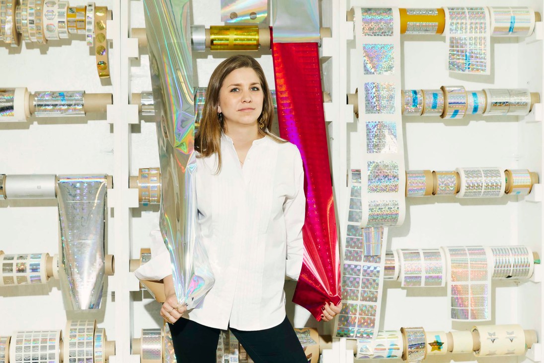 Martina Müller, CEO of 3d ag, holding holographic security tapes in front of wall of product samples