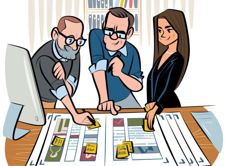 Illustration of three people collaborating at a wooden desk with design layouts and shelves of books in the background.