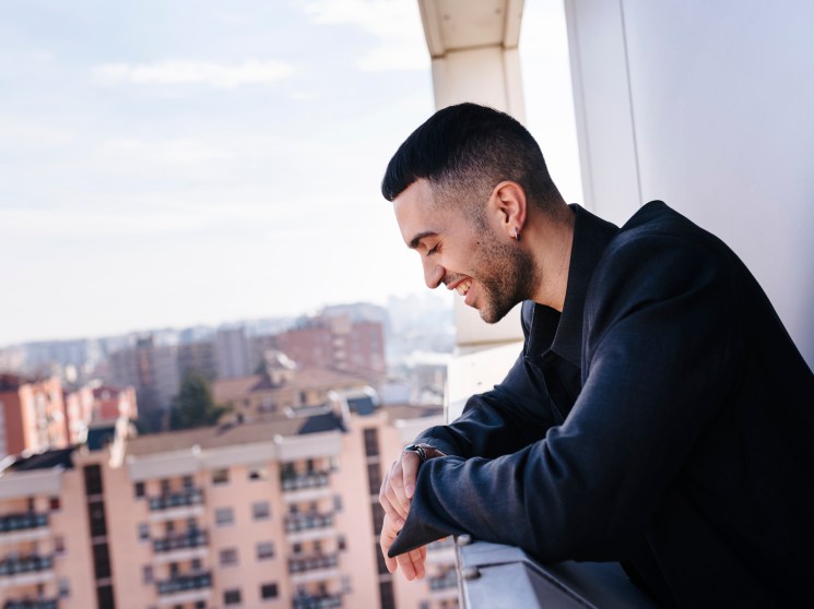 man smiling looking down from a balcony onto the city