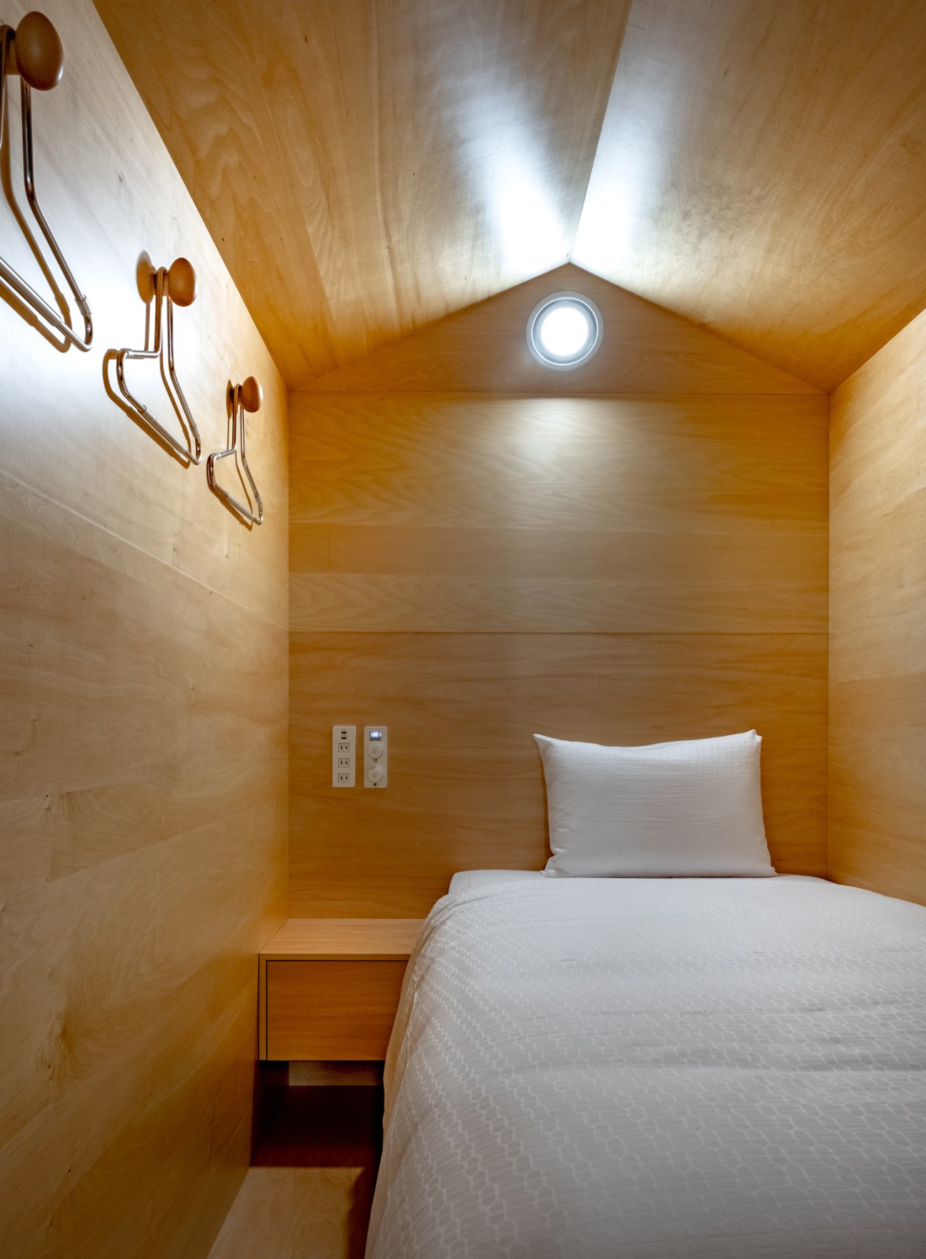 Interior view of a wooden sleeping pod at Maja Hotel Kyoto with white bedding and minimalist Nordic design