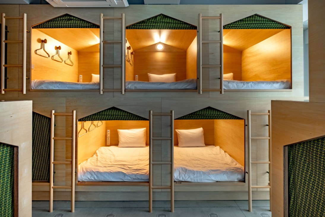 Interior view of Maja Hotel Kyoto's wooden sleeping pods with comfortable bedding and Nordic design details