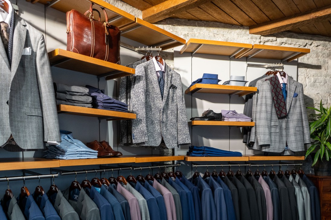 Interior of Gowri menswear boutique showing suits hanging on racks and shelves with folded clothing