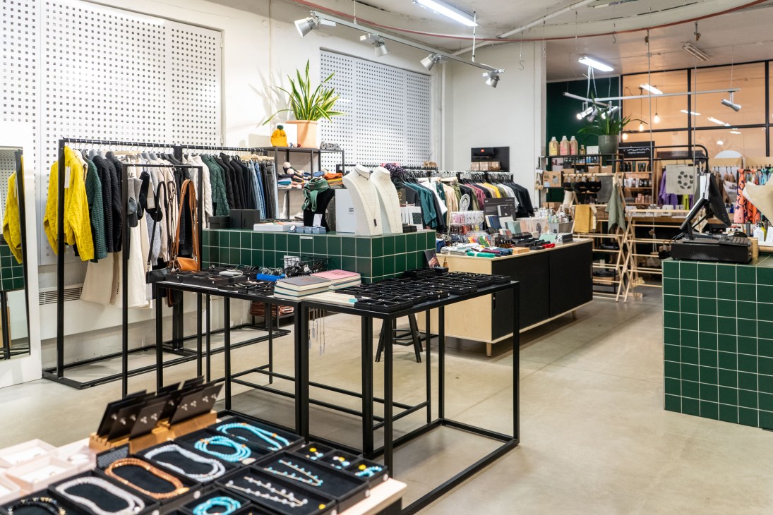 Modern retail interior with clothing racks, green tiled counter, and display tables in Telliskivi creative district
