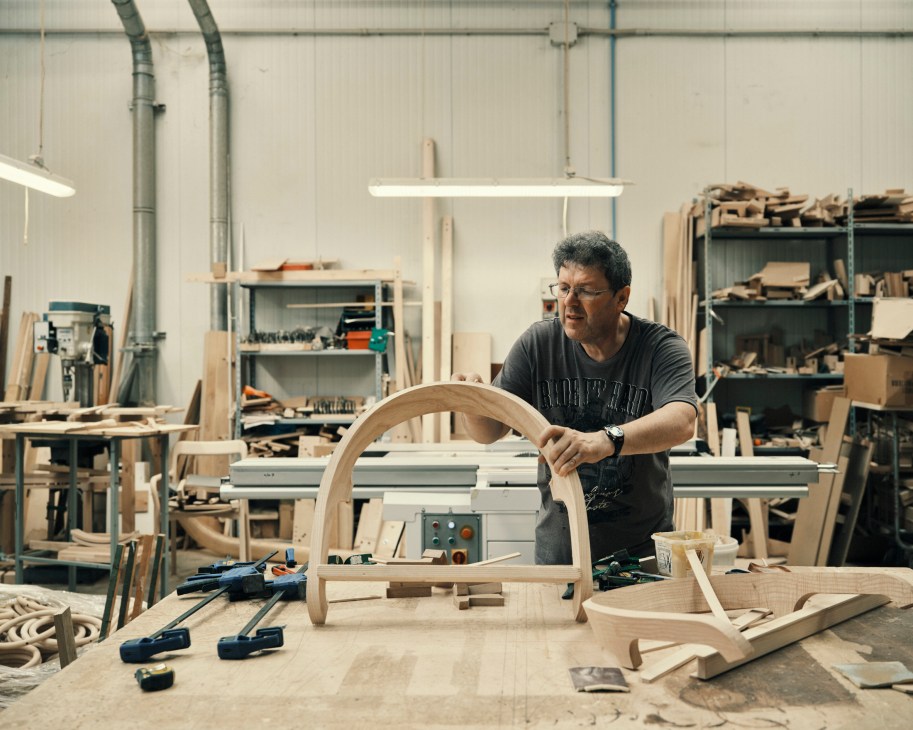 Craftsman Walter Vogrig working on a curved wooden chair component in the Mattiazzi factory workshop