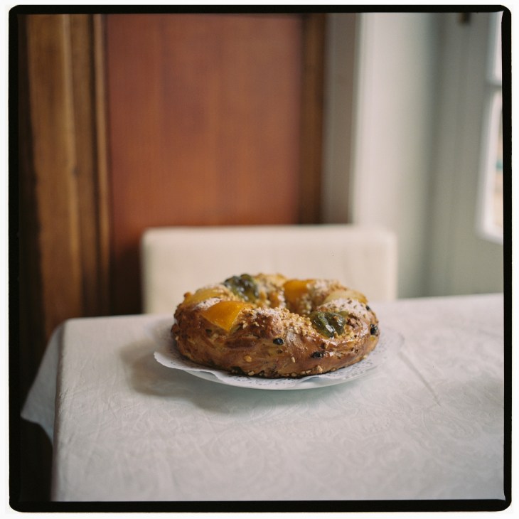 Portuguese bolo rei king cake with candied fruit and nuts on a white plate.