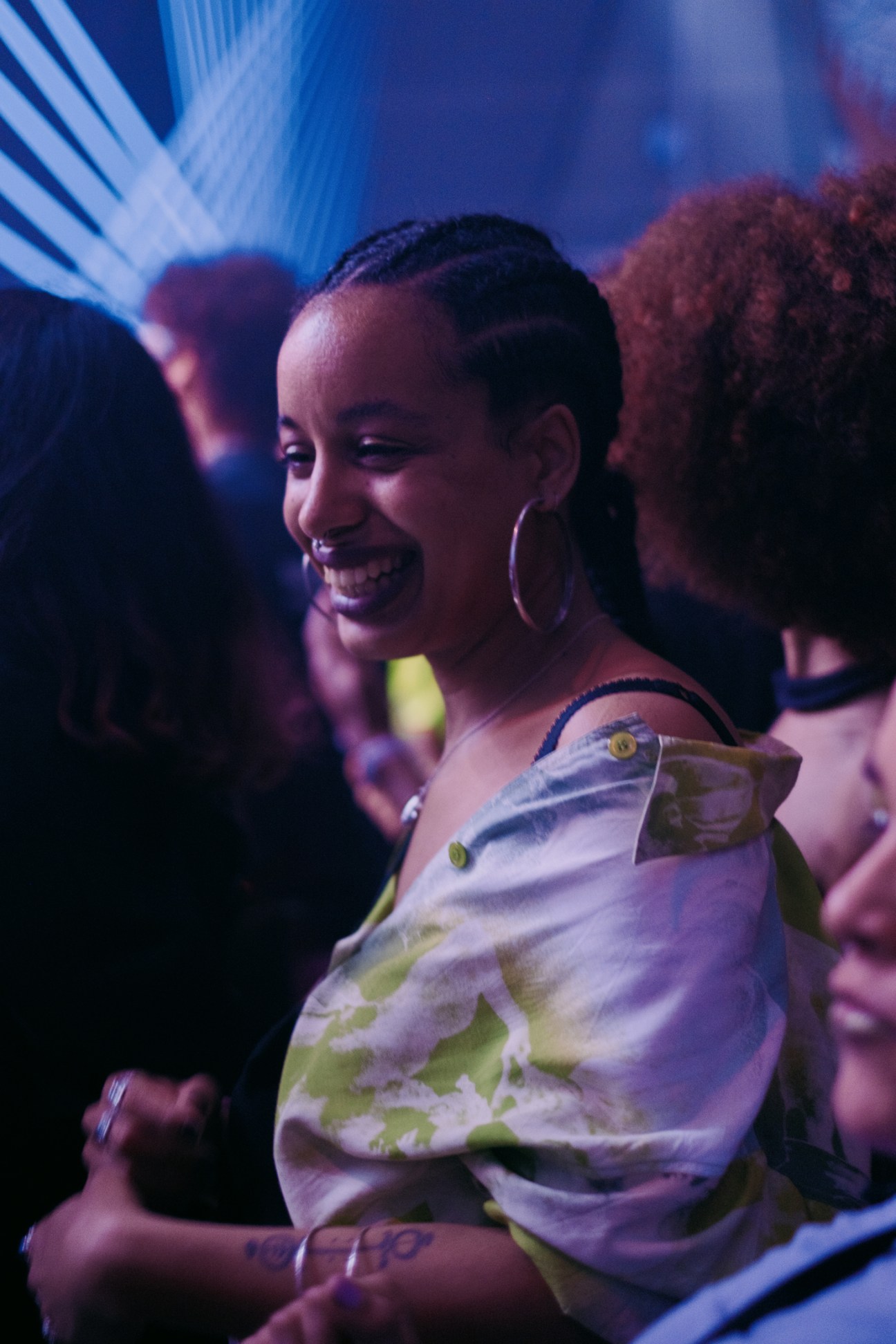 Smiling woman in white patterned shirt dancing in crowd during Nídia's performance at Sónar festival.