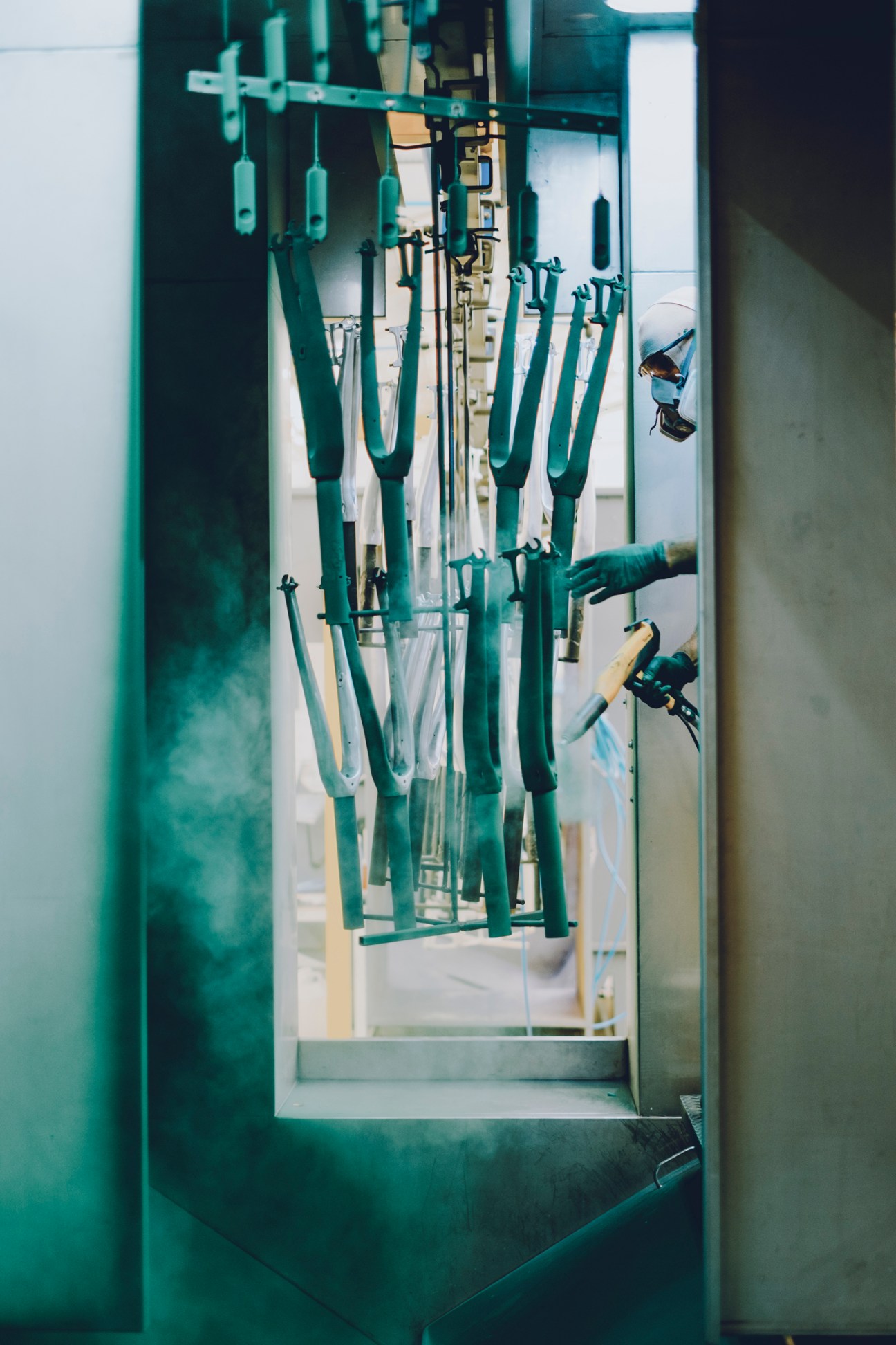 Bicycle frames hanging in a spray painting booth at a Portuguese manufacturing facility