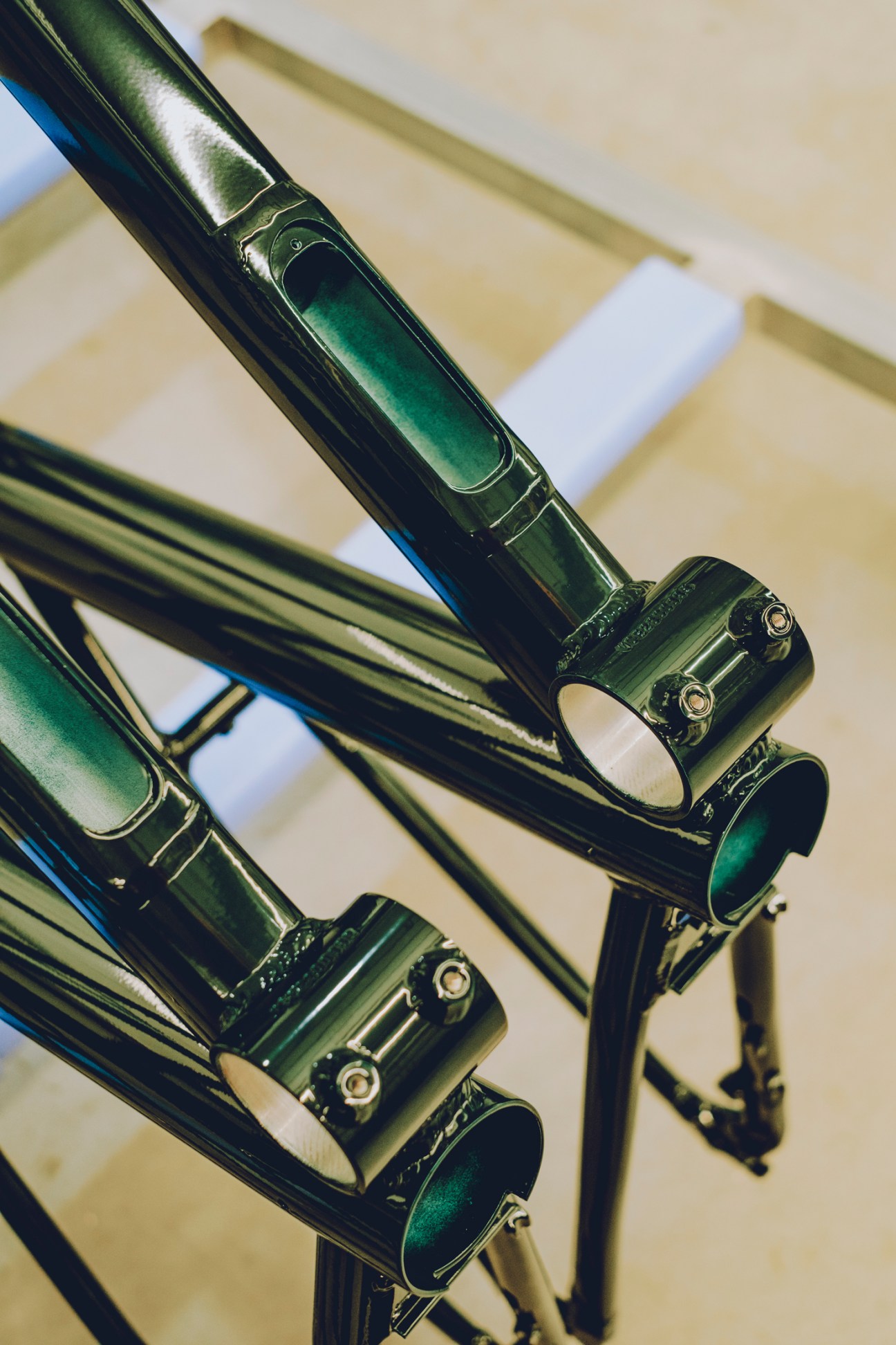 Close-up of green bicycle frame tubes with metal joining components showing manufacturing assembly details