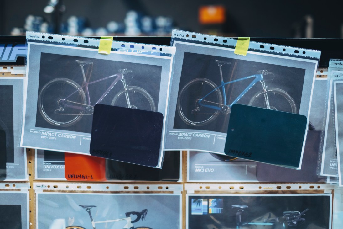 Bicycle marketing materials showing mountain bike models displayed on shelves with protective covers in a factory setting
