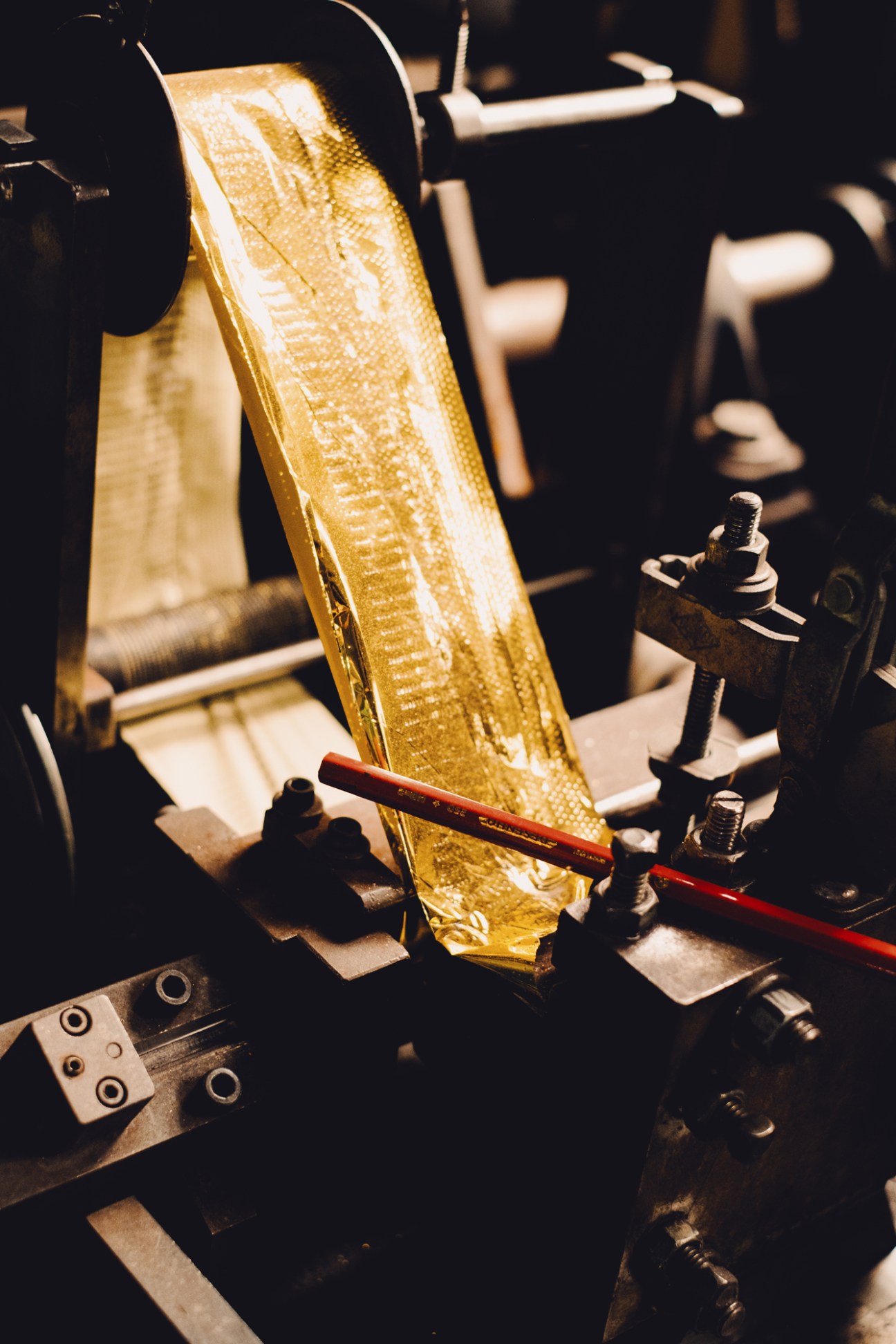 Golden pencil held in industrial machinery awaiting hot-stamp printing process