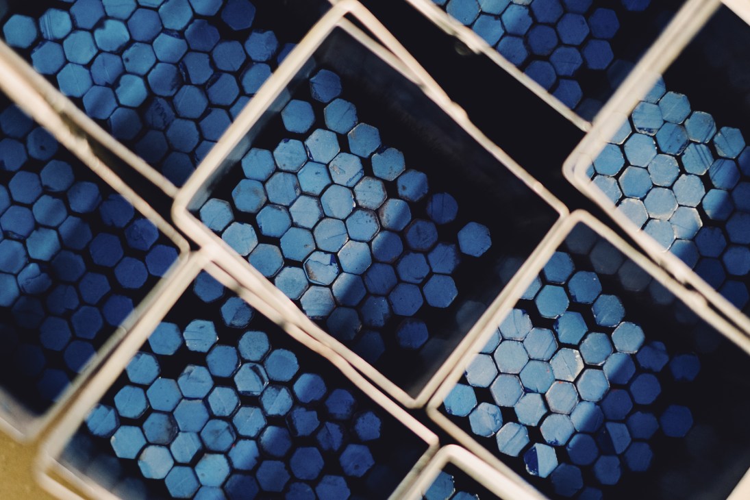 Blue hexagonal pastel pencil cores arranged in wooden compartmentalized trays