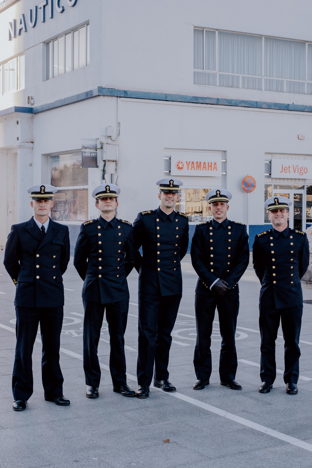 Five naval officers in dress uniforms standing in formation outside Clube Náutico in Vigo's port area