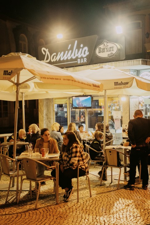 Outdoor terrace seating at a restaurant or café in Guimarães, Portugal, with yellow umbrellas and diners.