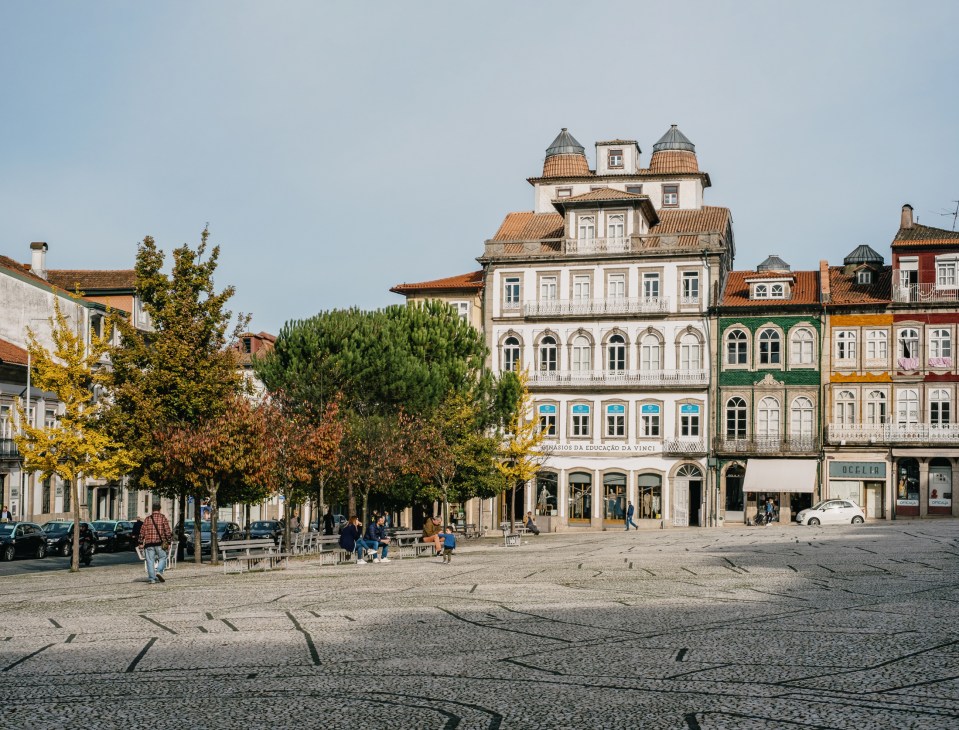 Guimarães historic town square with colorful buildings and people dining outdoors.