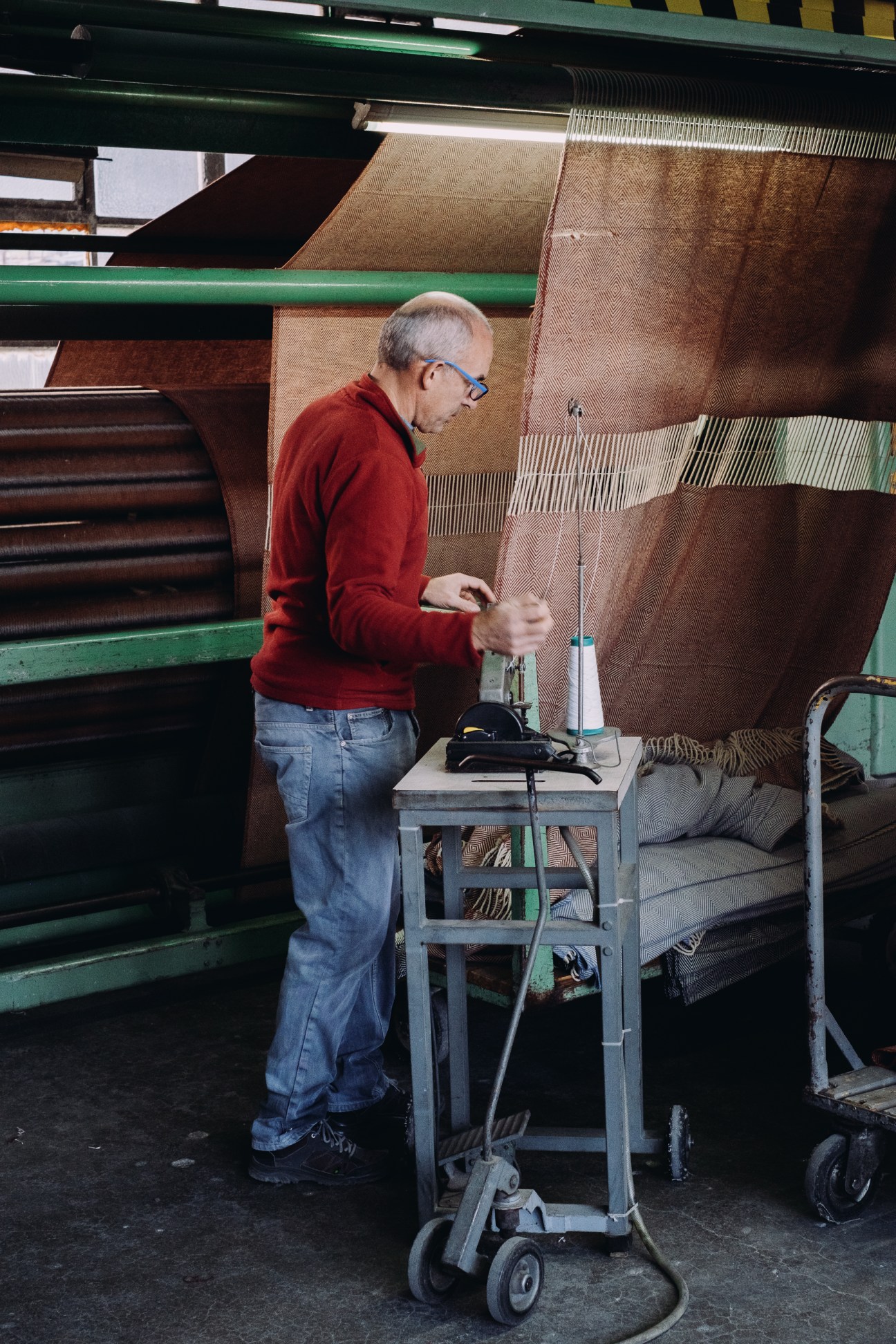 Man in red sweater operating wool processing machinery at A Transformadora textile factory in Covilhã, Portugal