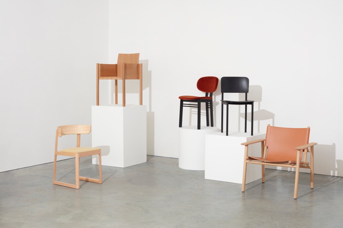 Collection of modern chairs displayed on white pedestals in studio setting