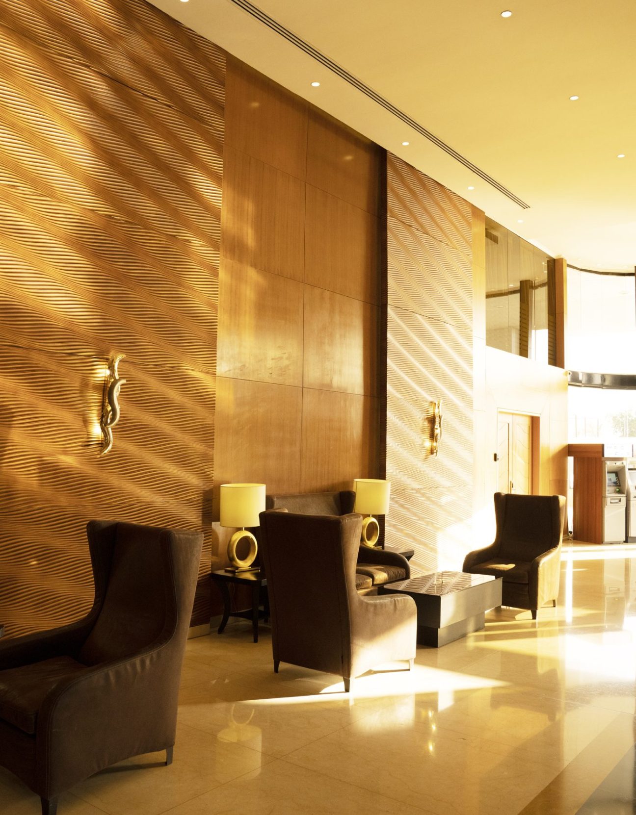 Elegant hotel lobby with textured wood walls, modern leather chairs, and warm golden lighting