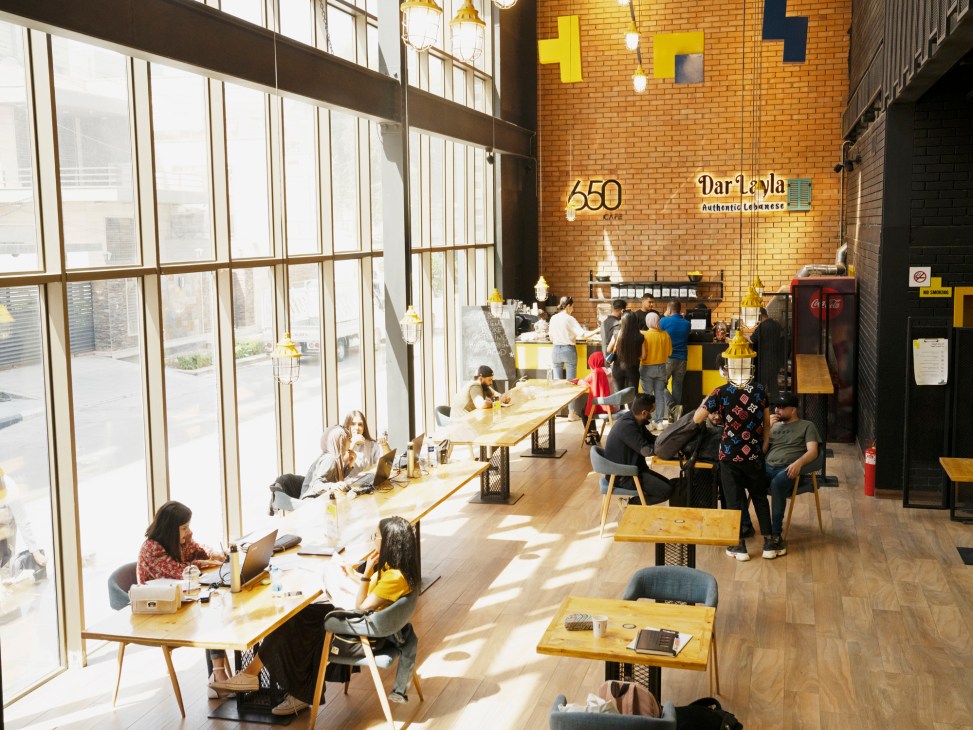 Modern café interior with exposed brick walls, pendant lighting, customers at tables and coffee counter