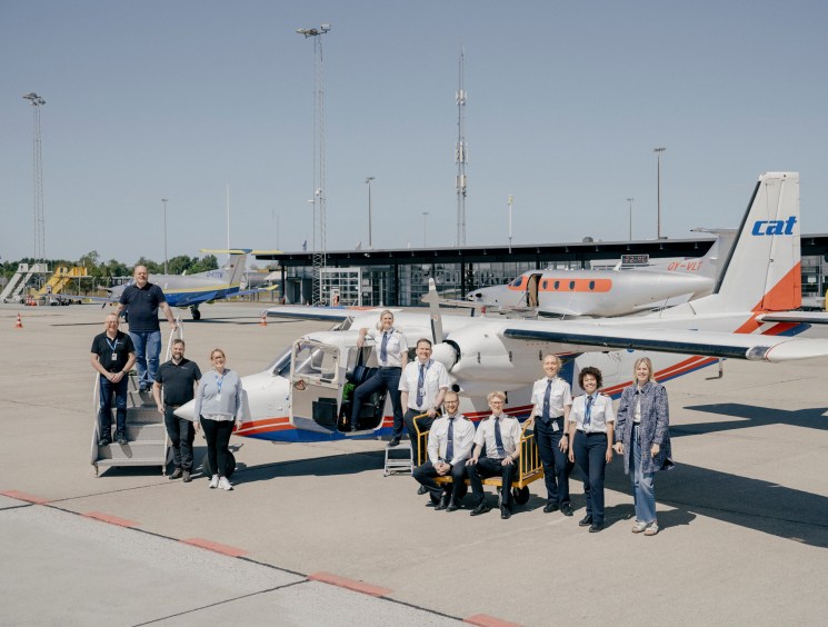 Group of pilots and staff posing with small aircraft on airport tarmac at Copenhagen Air Taxi training facility