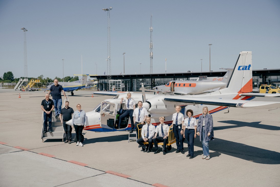 Group of pilots and staff posing with small aircraft on airport tarmac at Copenhagen Air Taxi training facility