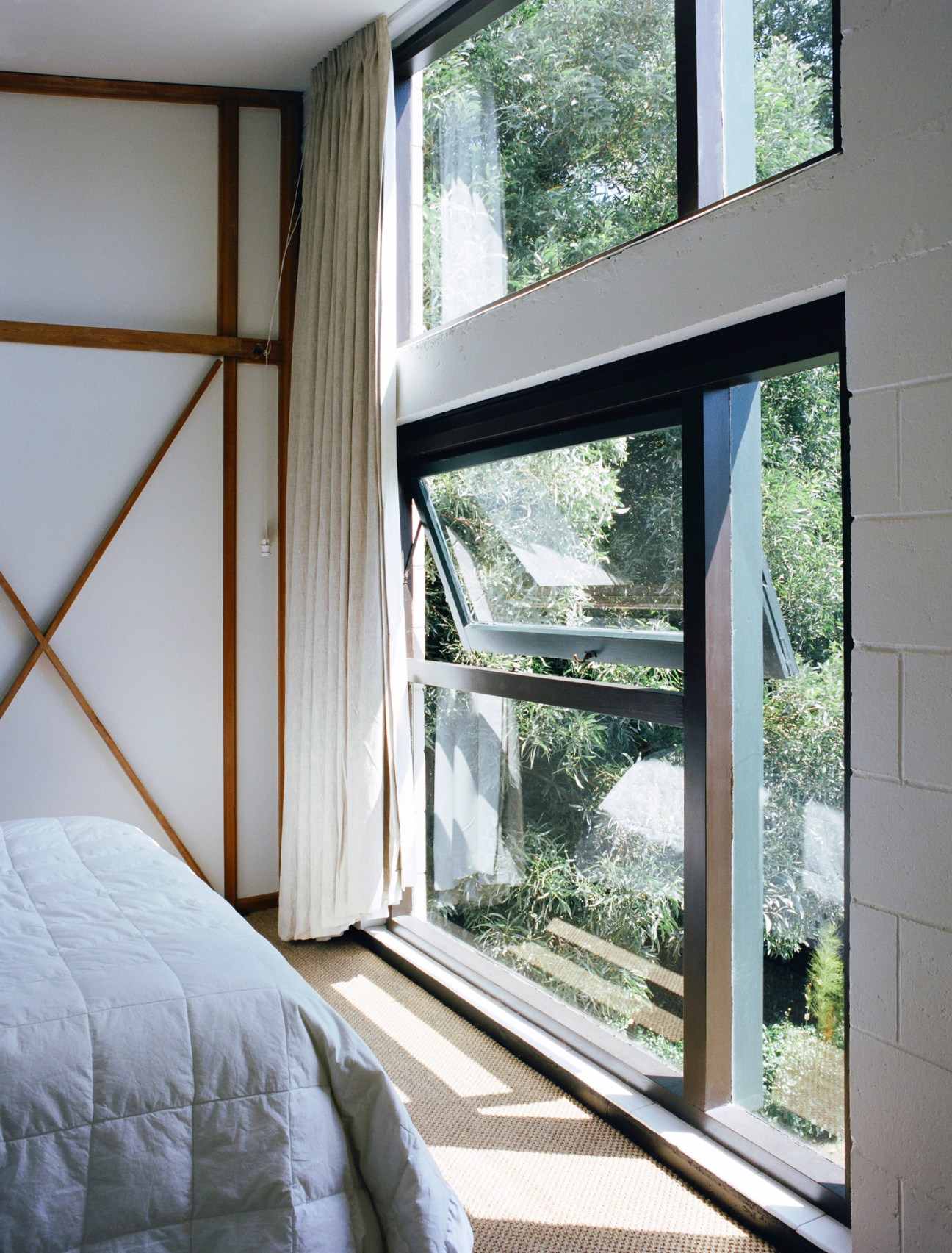 An upstairs bedroom with large windows looking into the trees