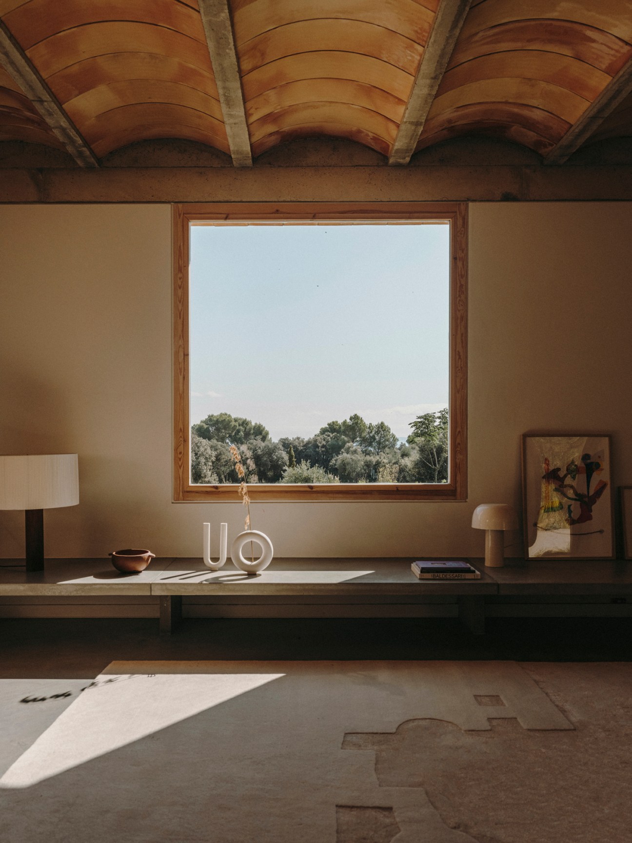Living room interior with ceramic ceiling, large window framing countryside landscape views.