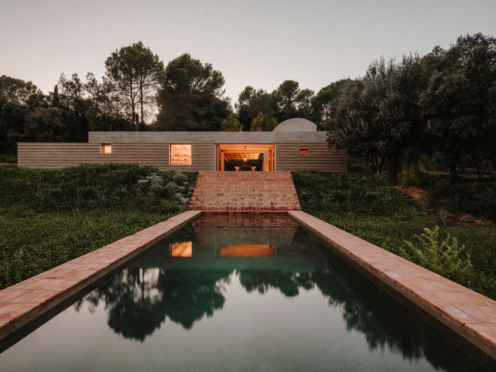 Casa Ter countryside residence with pool reflecting the modern wooden structure and surrounding trees.