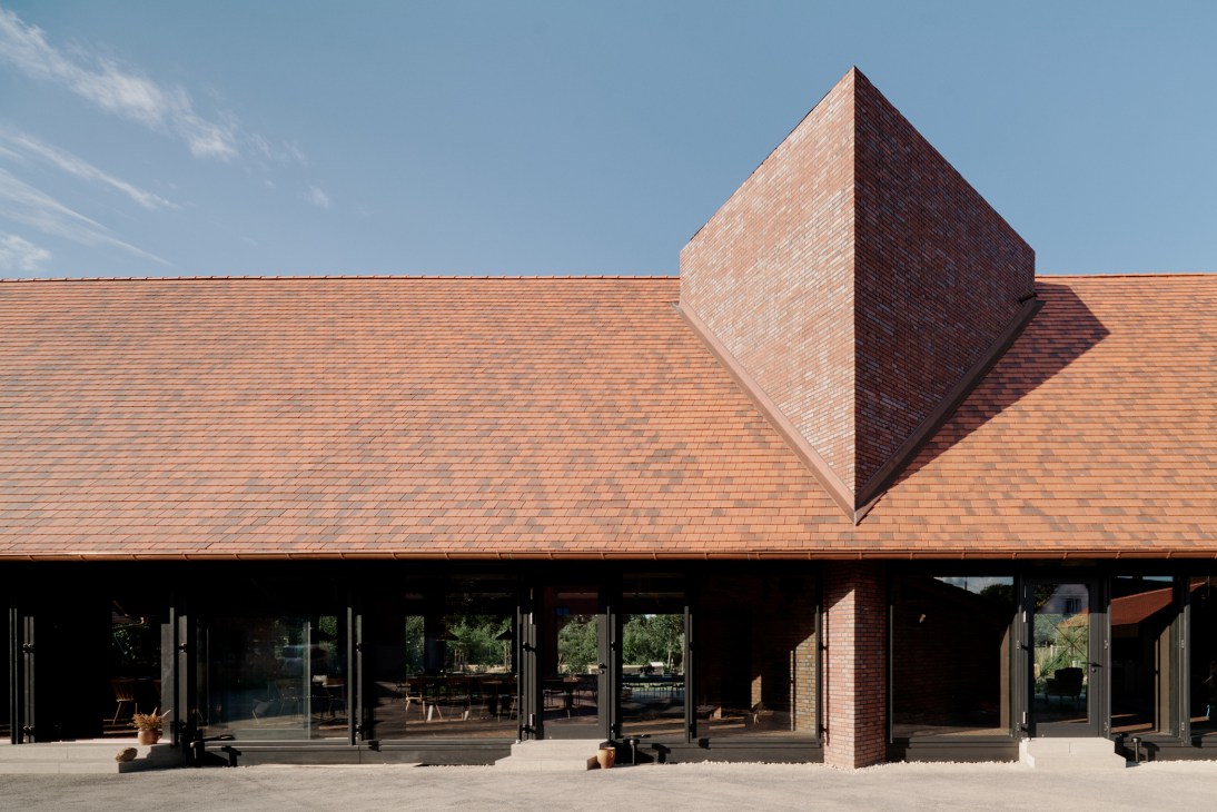 Michelberger Farm's brick restaurant building with geometric roof design and large windows overlooking the courtyard.
