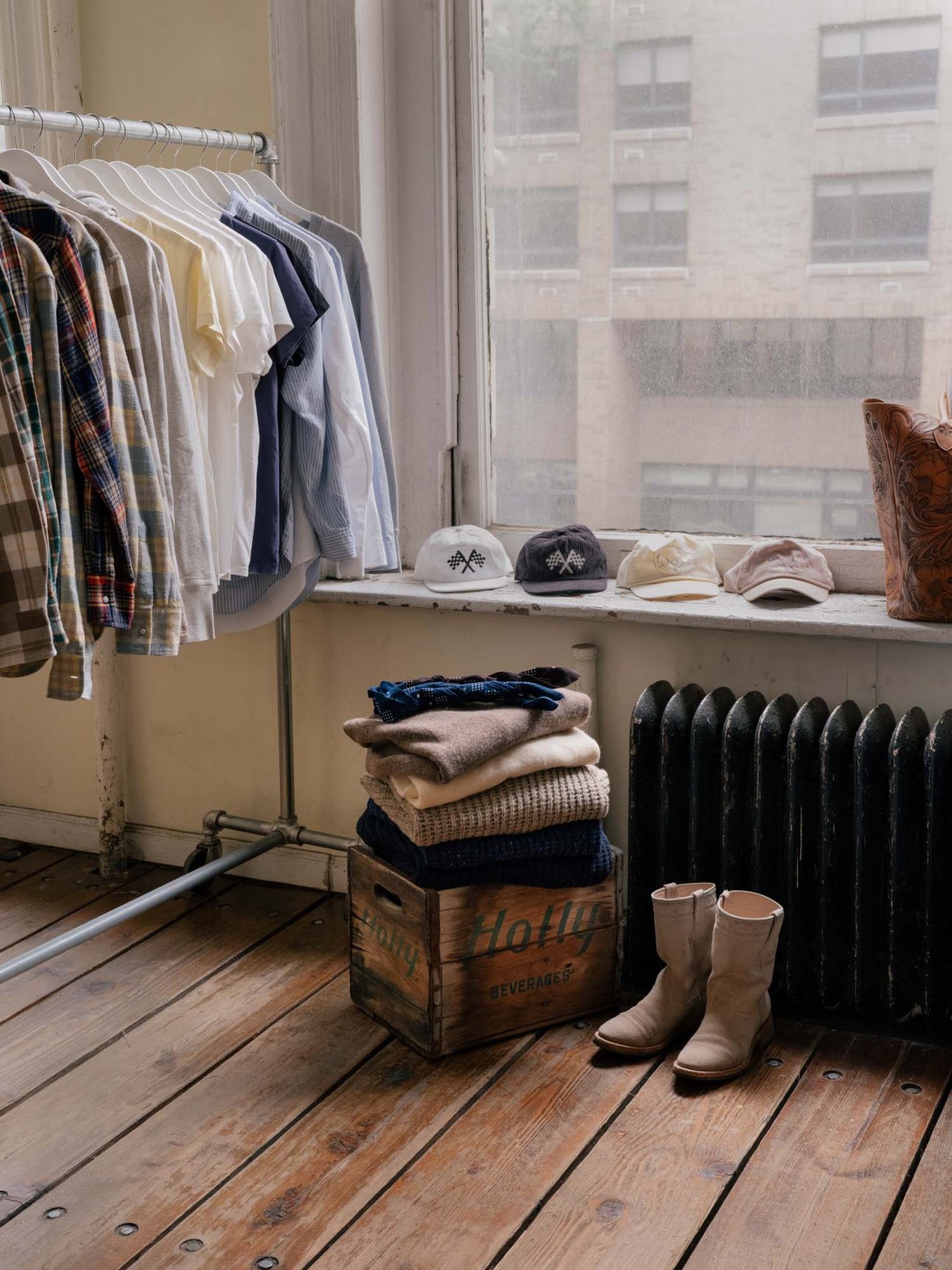 Wythe's collection of shirts, knitwear and accessories displayed on wooden surfaces near a window