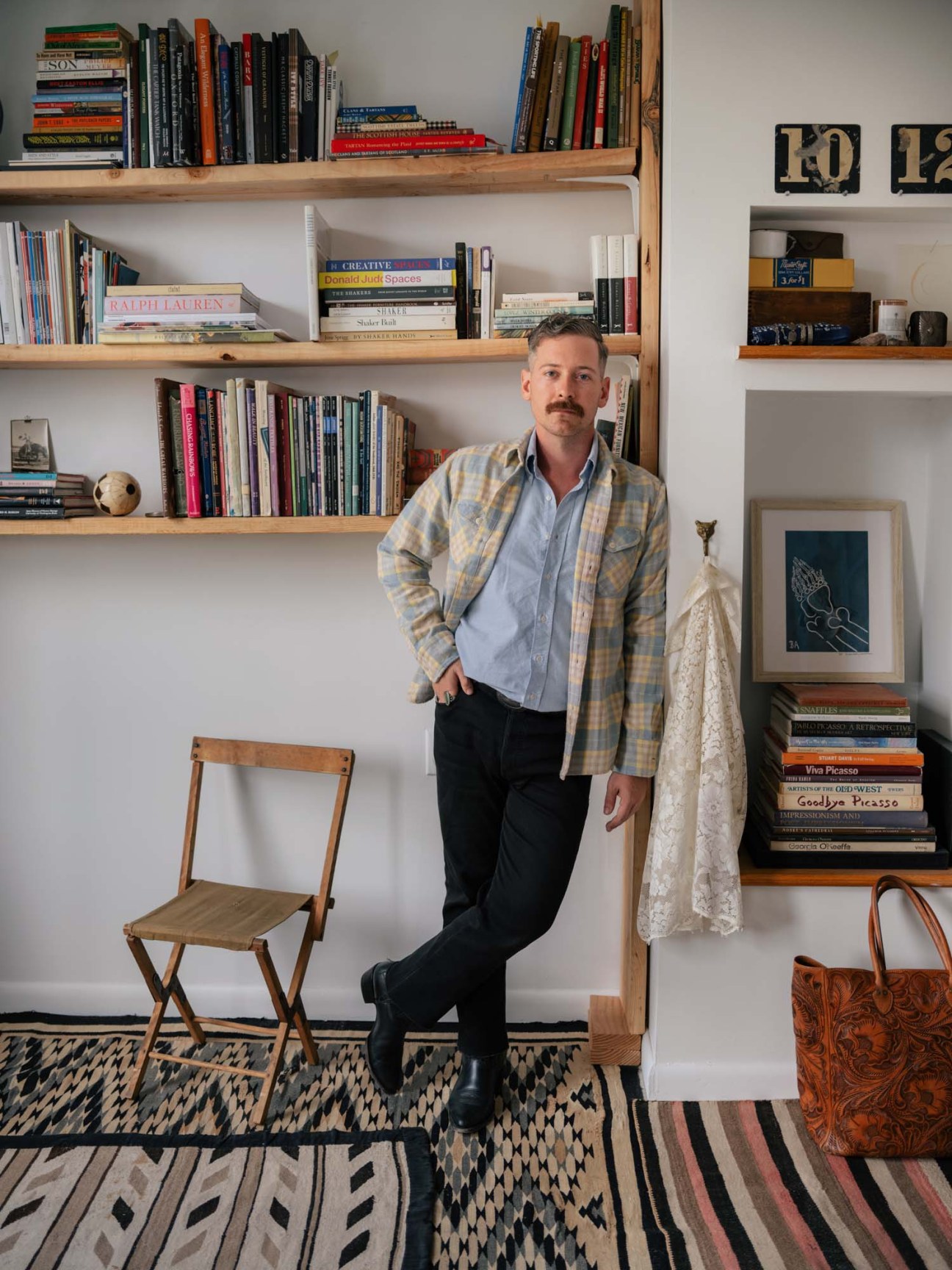 Peter Middleton, founder of Wythe, wearing a plaid overshirt and light blue shirt in front of bookshelves
