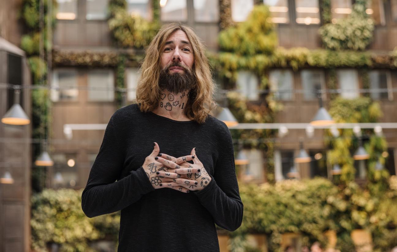 Micael Dahlen, professor with tattooed arms, sitting in modern academic office with contemporary art on walls