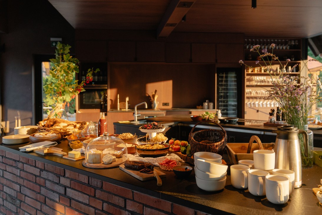 Sunlit kitchen counter displaying seasonal produce, bread, vegetables, flowers and tableware at Michelberger Farm.