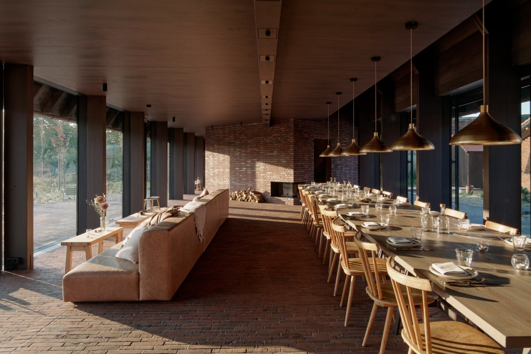 Michelberger Farm's modern restaurant interior with brick walls, wooden furniture, and brass pendant lights.