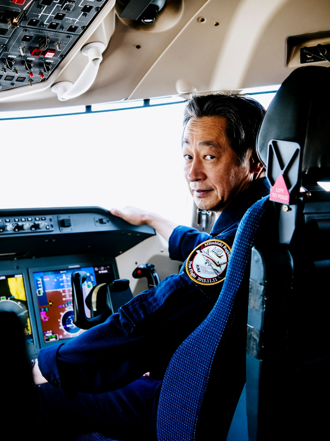Test pilot in SpaceJet cockpit with mission patch visible on flight suit