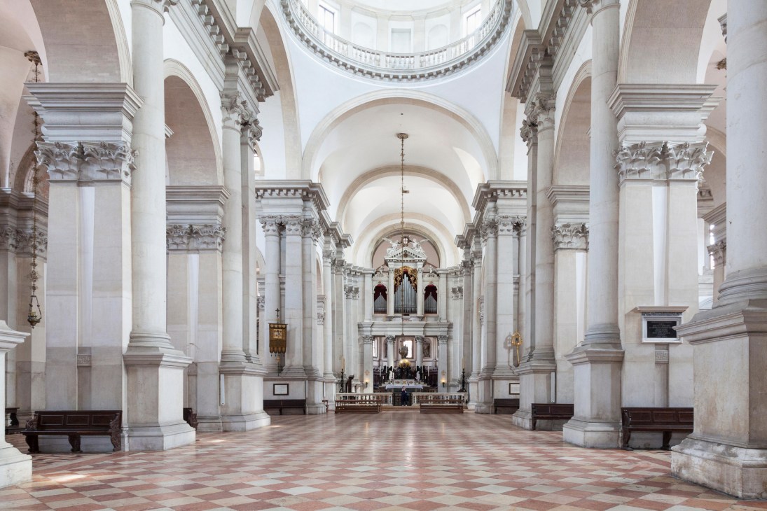 Interior of San Giorgio Maggiore church in Venice showing white columns, arched ceiling and altar